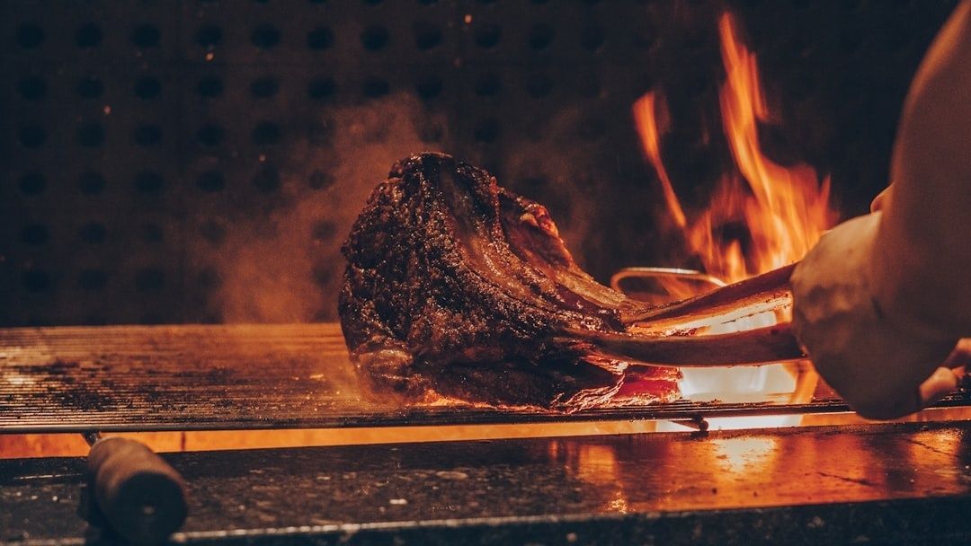 Un cuisinier découpe une pièce de viande flambée sur un guéridon